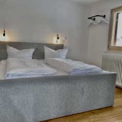 Gemütliches Schlafzimmer in Bad Wiessee Ferienwohnung mit bequemen Betten, moderner Beleuchtung und stilvollem Dekor, ideal für Entspannung.