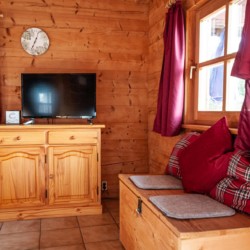 Gemütliches Holzinterieur eines Chalets in Schliersee mit TV und Sitzbereich. Ideal für eine entspannte Auszeit.