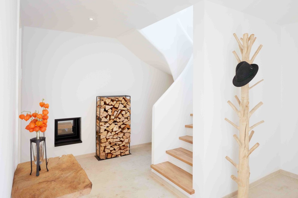 Helles, modernes Interieur einer Ferienwohnung in Kreuth mit stilvoller Treppe und Kaminholz. Ideal für eine Auszeit in der Natur.
