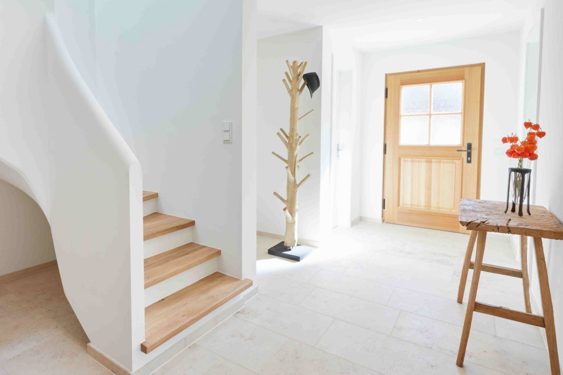 Helle Ferienwohnung in Kreuth: einladender Eingangsbereich mit Treppe und natürlichem Dekor. Ideal für Erholungssuchende.