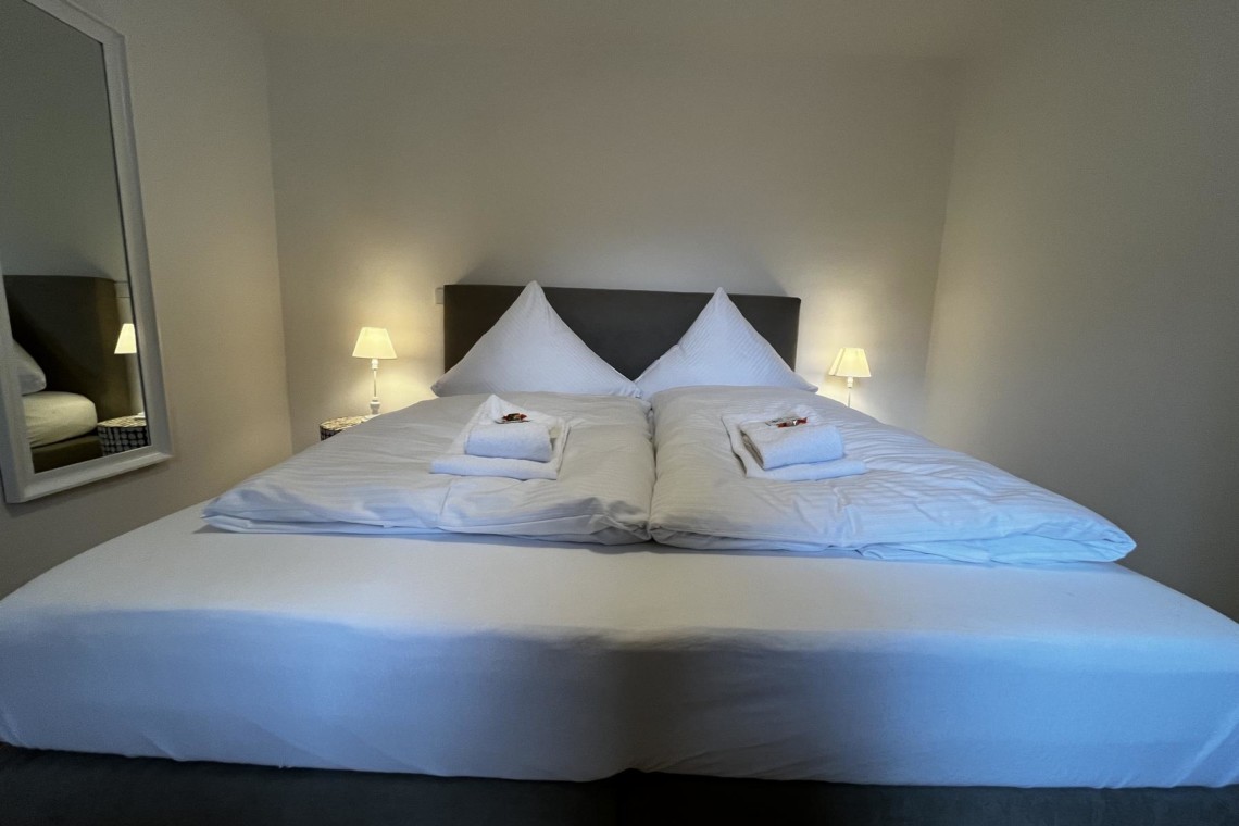 Gemütliches Doppelbett, sauber und einladend, in einer Ferienwohnung in Bayrischzell - perfekt für Erholungssuchende.