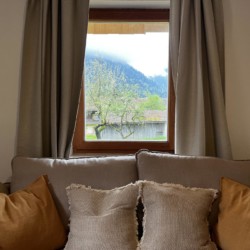 Gemütlicher Raum mit Sofa, Kissen und Blick auf Berge, ideal für Entspannung in Bayrischzell.