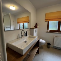 Helles Badezimmer in Ferienwohnung in Rottach-Egern mit moderner Einrichtung und warmen Farbtönen.