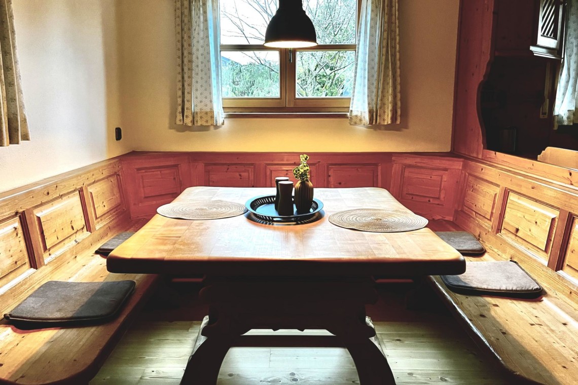 Gemütliche Essecke im bayerischen Stil, Holztisch, Fensterblick, ideal für Urlaub in Rottach-Egern.
