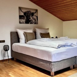 Gemütliches Schlafzimmer im Ferienhaus am Tegernsee, stilvoll mit Holzdecke und Kunst.