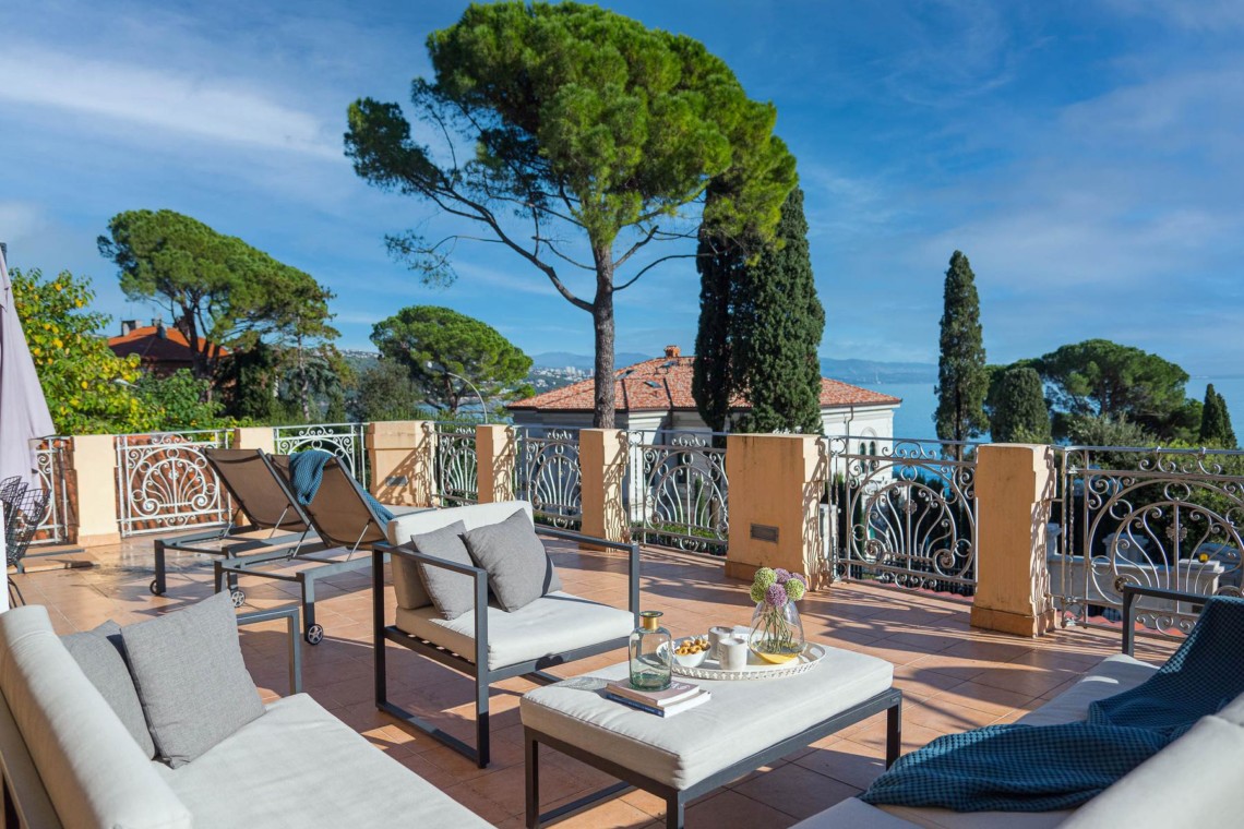 Charmante Terrasse eines Luxus-Apartments in Opatija mit eleganten Sitzmöbeln, Meerblick und umgeben von Grün.
