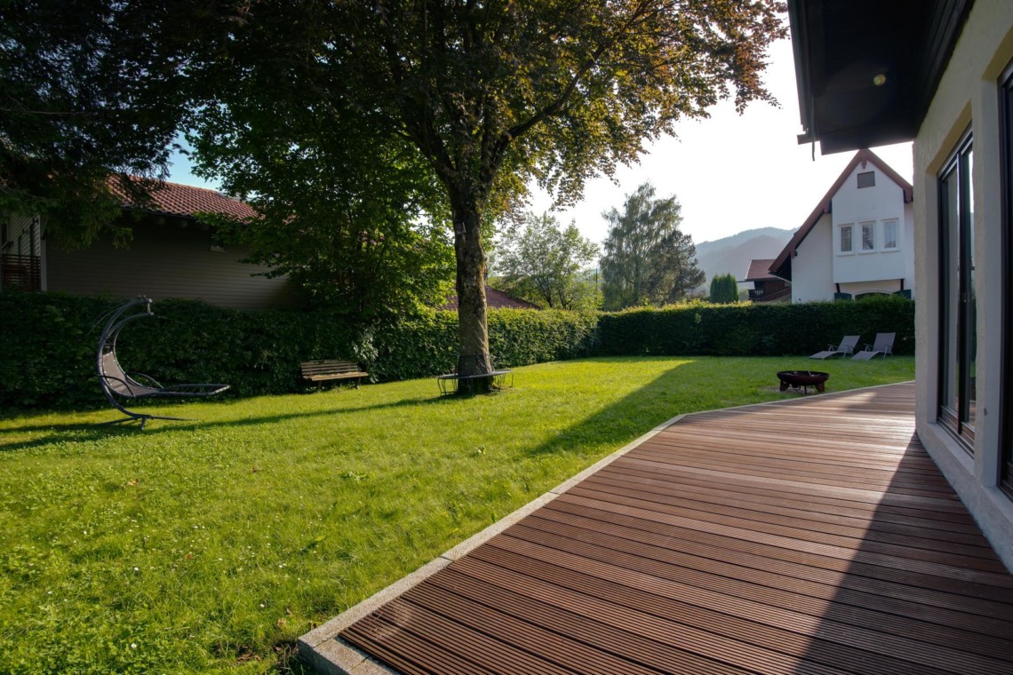 Gemütlicher Garten einer Ferienwohnung "Perfall17" in Schliersee mit Holzdeck und Liegestühlen. Ideal für Erholung.