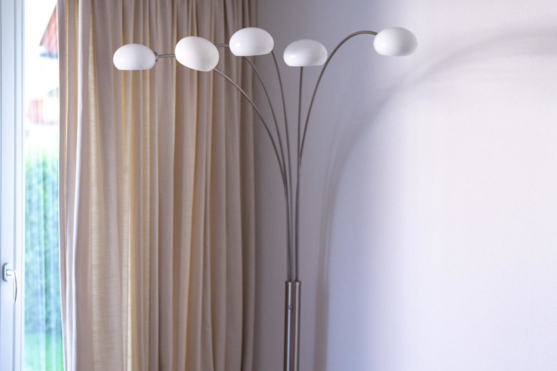 Gemütliches Zimmer in "Villa Perfall17" Schliersee mit moderner Lampe, elegantem Vorhang und Holzhocker – Ihr Urlaubszuhause!