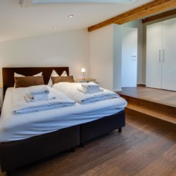 Gemütliches Schlafzimmer in Ferienwohnung am Schliersee, stilvoll eingerichtet mit Holzakzenten. Ideal für Erholungssuchende.