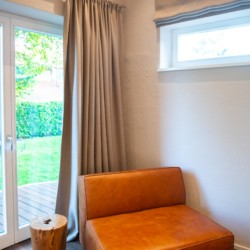 Gemütliches Ambiente in Schlierseer Ferienwohnung mit modernem Sessel und Gartenblick.