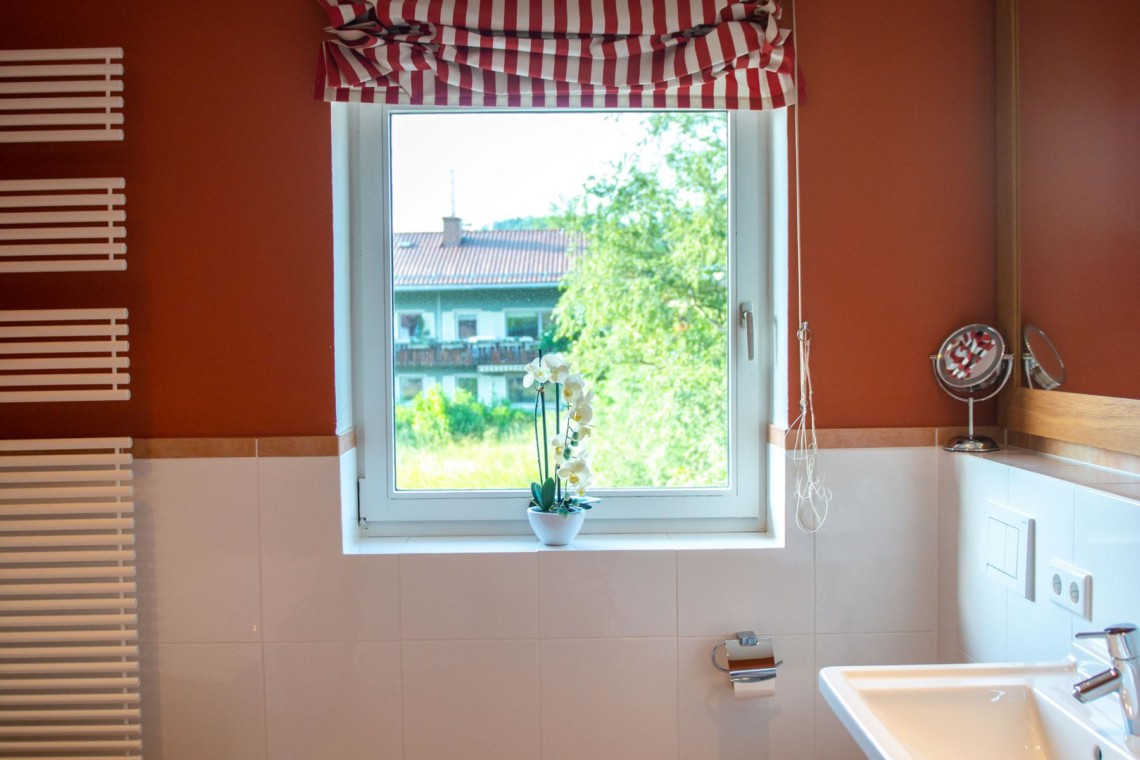 Gemütliches Badezimmer in Villa Perfall17, Schliersee mit modernen Annehmlichkeiten, warmem Dekor und Blick ins Grüne.