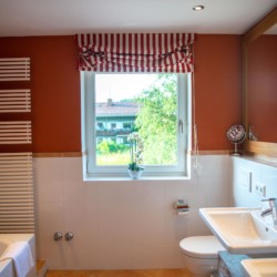 Gemütliches Badezimmer in Villa Perfall17, Schliersee mit modernen Annehmlichkeiten, warmem Dekor und Blick ins Grüne.