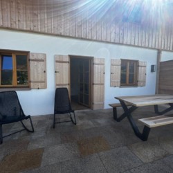 Gemütliche Terrasse einer Ferienwohnung in Kreuth mit Holzmöbeln, Grill, Sonnenschein – ideal für Erholung.