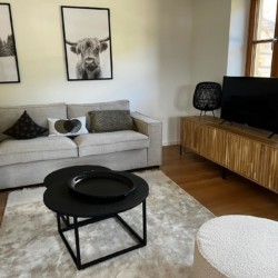 Gemütliches Wohnzimmer in Kreuth mit Sofa, Fernseher & modernem Dekor für entspannten Urlaub in der Natur. Buchen Sie jetzt!