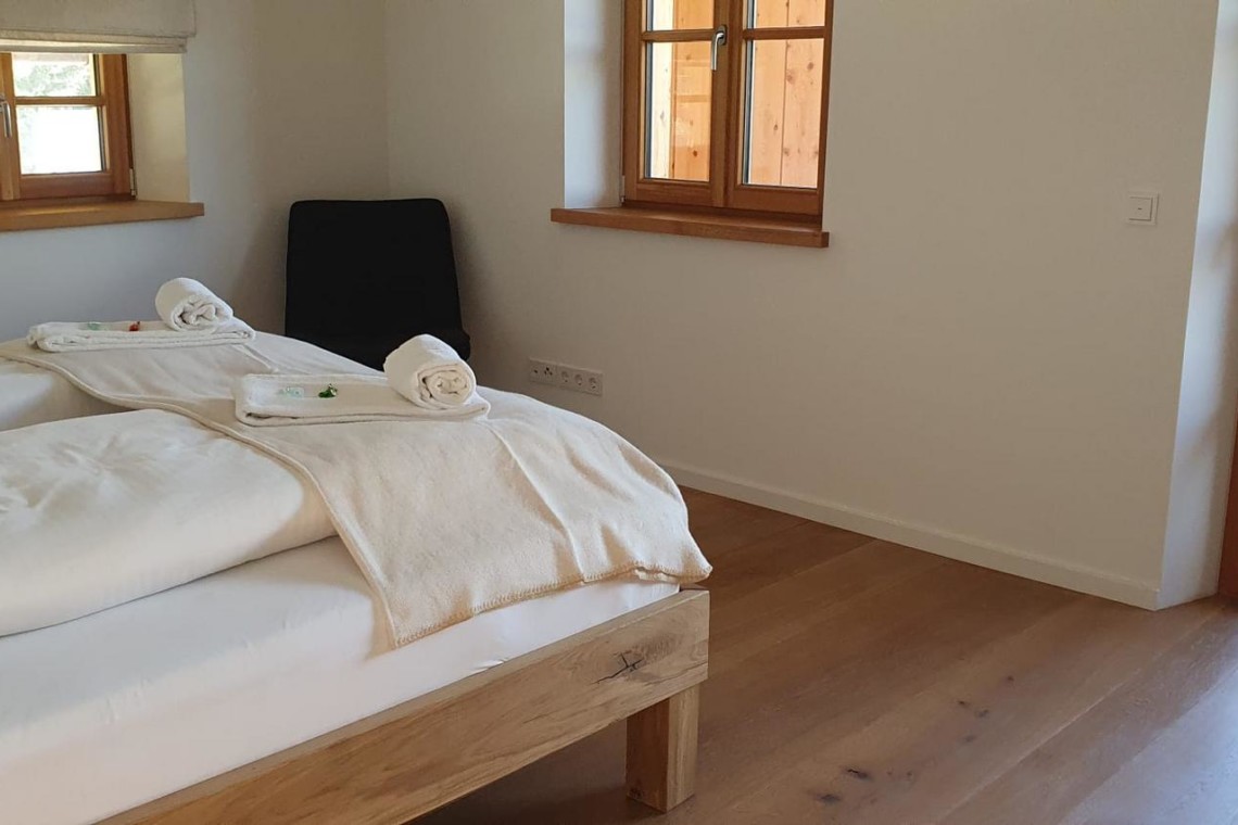 Gemütliches Schlafzimmer in Kreuth Ferienwohnung mit Balkontür und Holzakzenten.