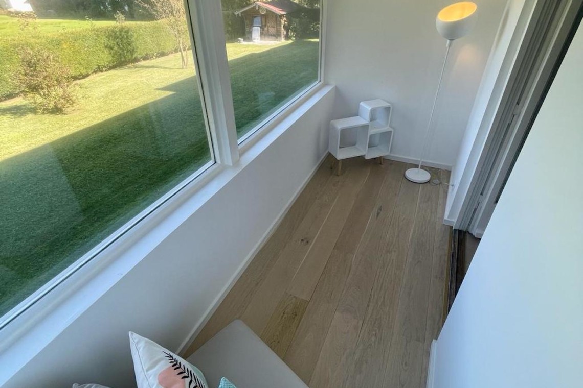 Gemütlicher Raum einer FeWo in Bad Wiessee mit Bergblick, hellem Interieur und direktem Zugang zum grünen Garten. Ideal für Entspannung.