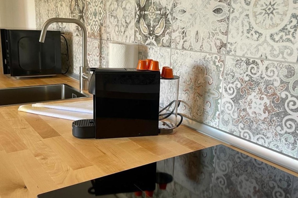 Gemütliche, moderne Küche in FeWo mit stilvollem Backsplash und Induktionskochfeld. Idealer Komfort für Urlaub in Bad Wiessee.