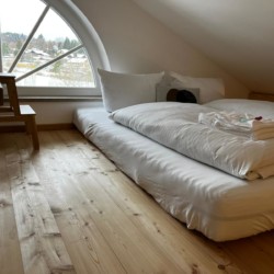 Gemütliches Dachzimmer mit Bett und Holzboden in Ferienwohnung in Gmund am Tegernsee.