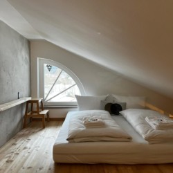 Gemütliches Dachzimmer mit Holzfußboden und großem Bett in Gmund, ideal für Tegernsee-Urlaub.