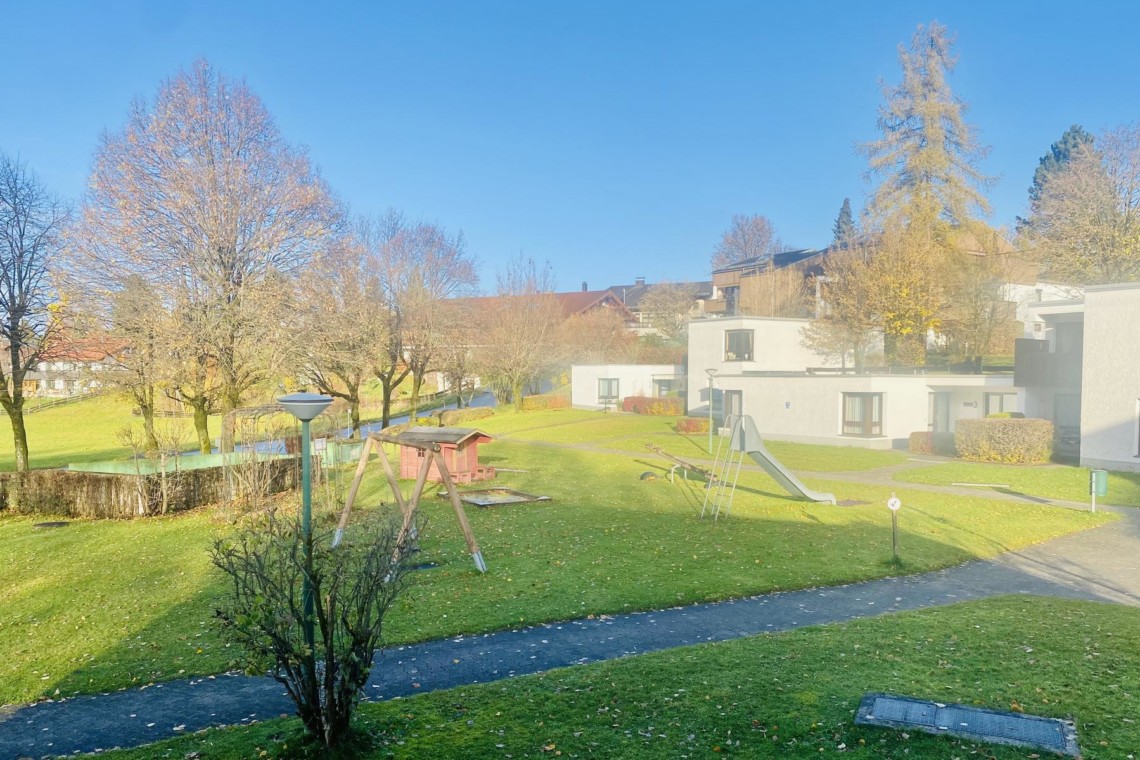 Sonniger Blick aus Ferienwohnung in Schliersee mit Spielplatz und grünen Wiesen. Ideal für Erholung und Familien.