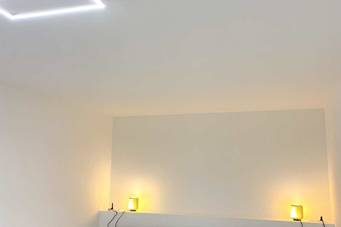 Gemütliches Schlafzimmer in Bad Wiessee Ferienwohnung mit moderner Beleuchtung und komfortablem Bett. Ideal für Erholungssuchende.