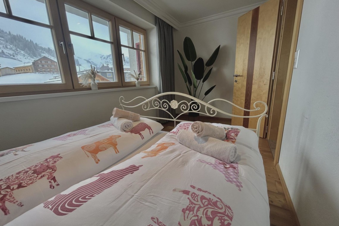 Gemütliches Schlafzimmer in der Ferienwohnung Hillside One, Warth am Arlberg, mit Alpenblick.