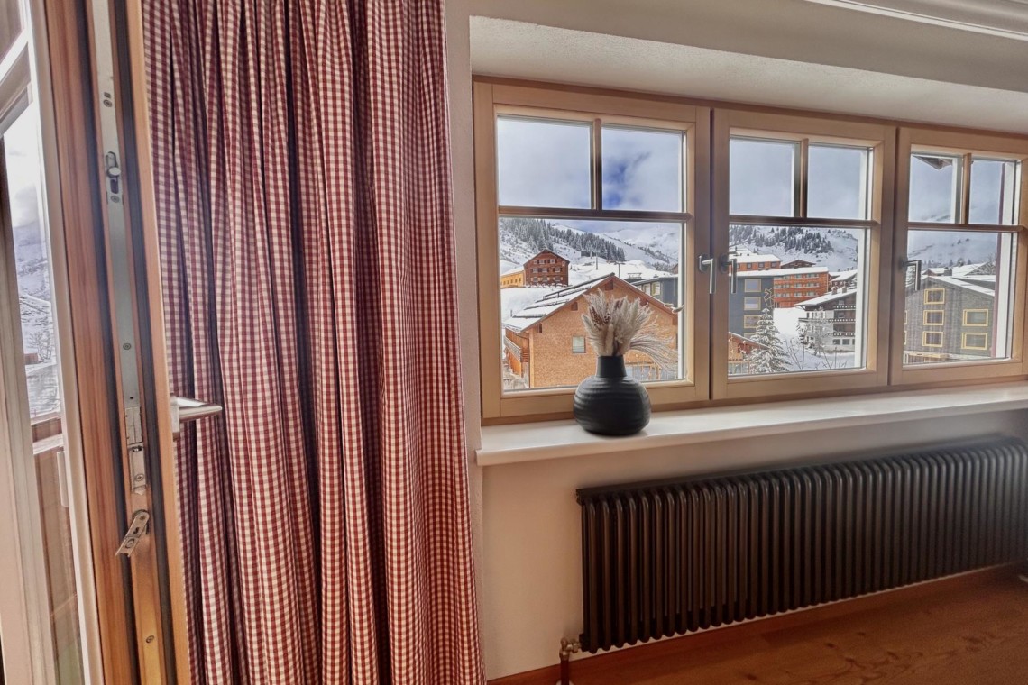 Gemütliches Ferienapartment mit Blick auf verschneite Dächer in Warth am Arlberg, ideal für den Bergurlaub.