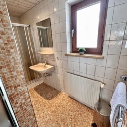 Gemütliches Ferienapartment-Badezimmer in Warth am Arlberg mit Dusche und Holzelementen für eine Wohlfühlatmosphäre.