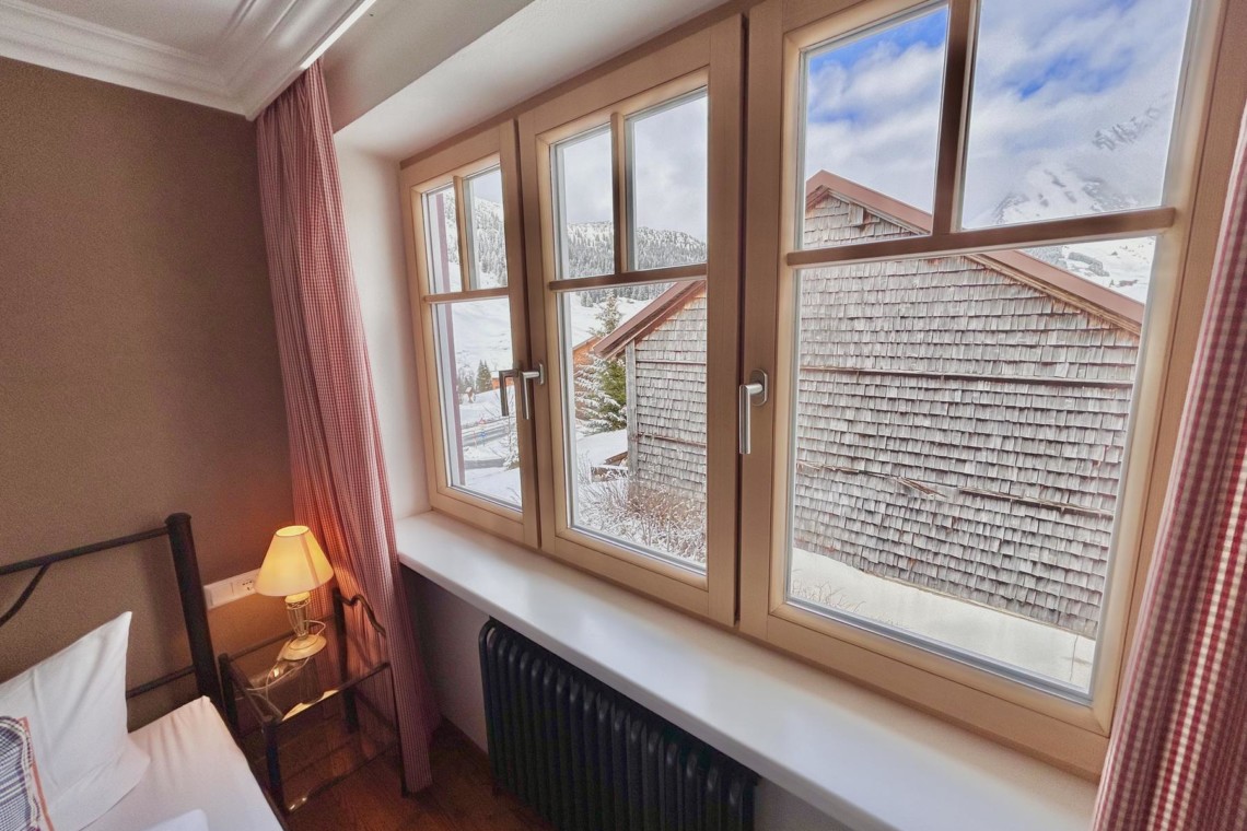 Gemütliches Zimmer in Hillside One, Warth am Arlberg, mit Blick auf Winterlandschaft. Ideal für Urlaub in den Alpen. #FerienwohnungWarthArlberg