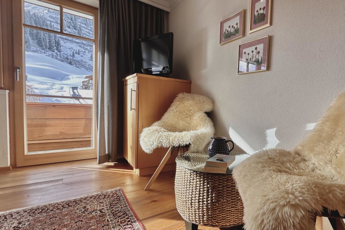 Gemütliches Wohnzimmer einer Ferienwohnung in Warth am Arlberg mit Aussicht auf schneebedeckte Berge.