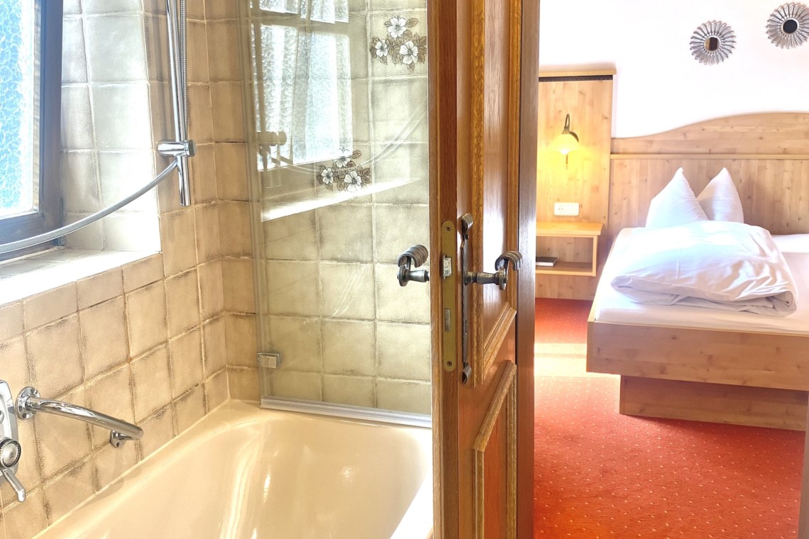 Gemütliches Schlafzimmer mit angrenzendem Bad in Schlierseer Ferienwohnung – ideal für erholsame Urlaubstage.