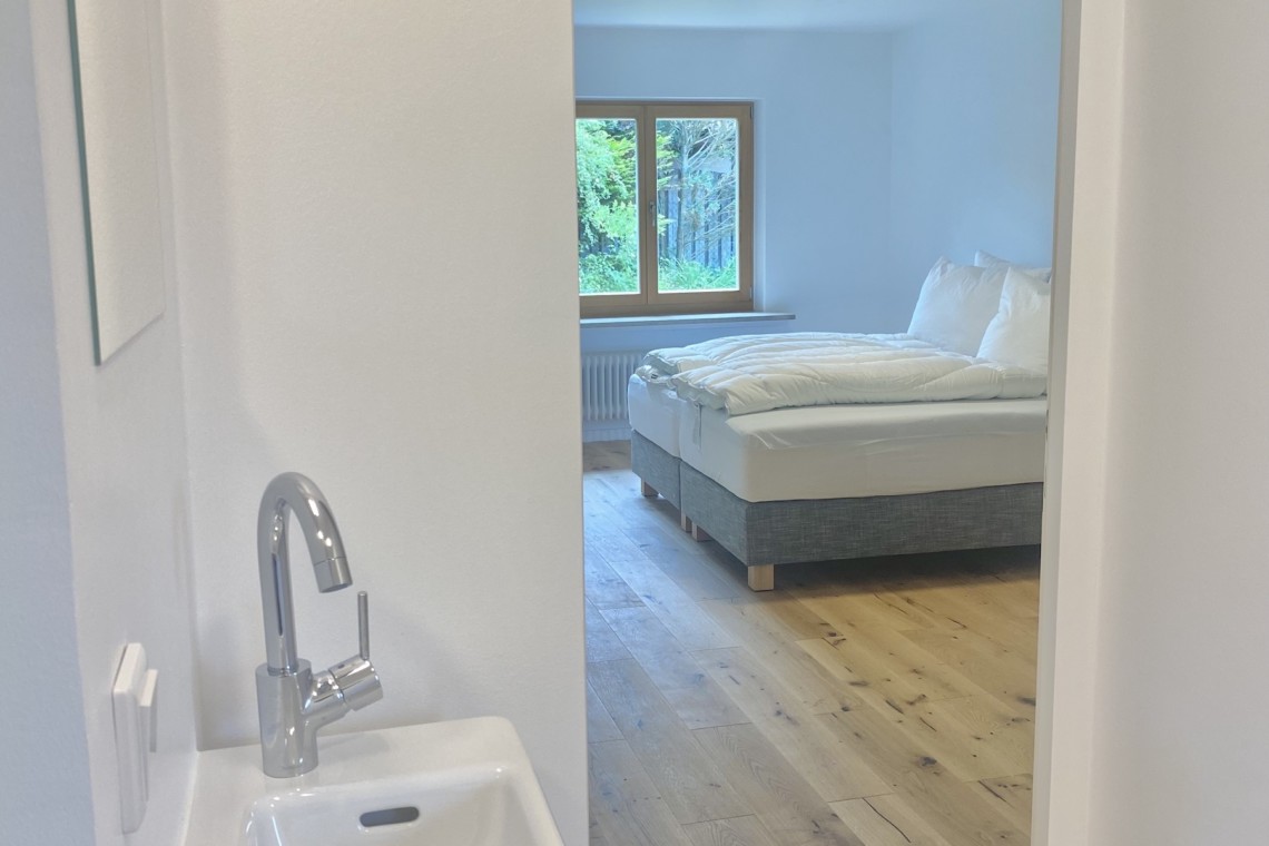 Helles, modernes Zimmer in Rottach-Egern, ideal für Ruhe und Arbeit. Gemütliches Bett mit Blick aufs Grüne.
