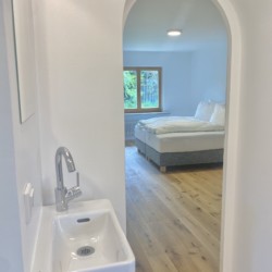 Helles, modernes Zimmer in Rottach-Egern, ideal für Ruhe und Arbeit. Gemütliches Bett mit Blick aufs Grüne.