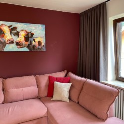 Gemütliches Apartment in Tegernsee, mit rosa Sofa & Kuhbild, ideal für eine entspannten Aufenthalt. Buchen Sie jetzt auf stayfritz.com!