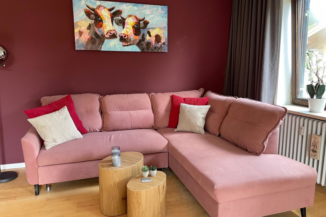 Gemütliches Apartment in Tegernsee mit rosa Couch, Kunstwerk und modernem Dekor – ideal für eine entspannte Auszeit.
