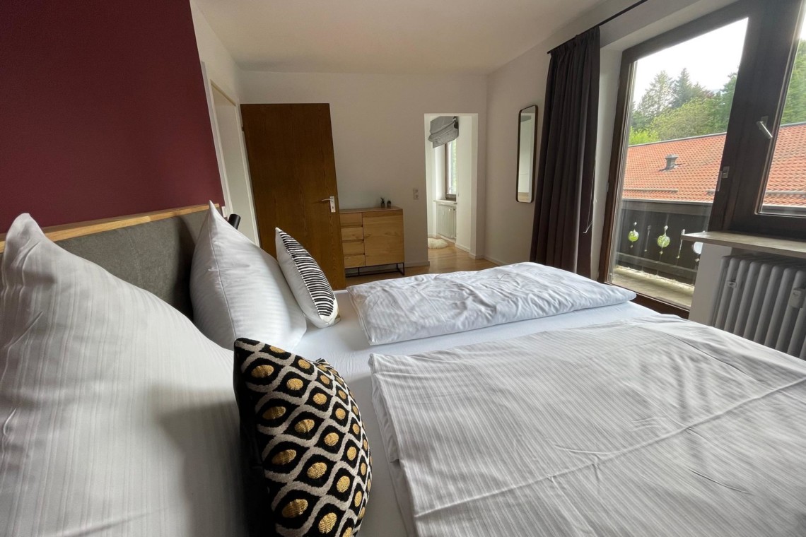 Gemütliches Schlafzimmer mit Doppelbett in heller Ferienwohnung am Tegernsee, ideal für Urlaub.