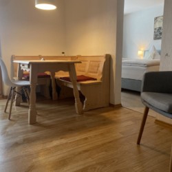 Gemütliches Wohnzimmer einer FeWo in Bad Wiessee mit Esstisch, Couch & Holzboden.