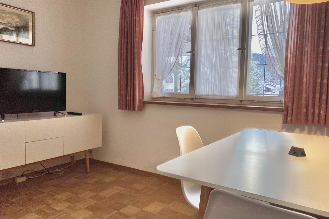Gemütlich-rustikales Wohnzimmer einer FeWo in Bad Wiessee mit TV und Essbereich.