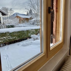 Gemütlicher Blick aus einem Fenster auf verschneite Landschaft in Bad Wiessee. Ideal für Urlaub am Tegernsee.