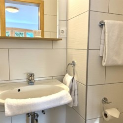 Helle, moderne Ferienwohnungs-Badezimmer in Bad Wiessee mit Spiegel und Handtüchern.