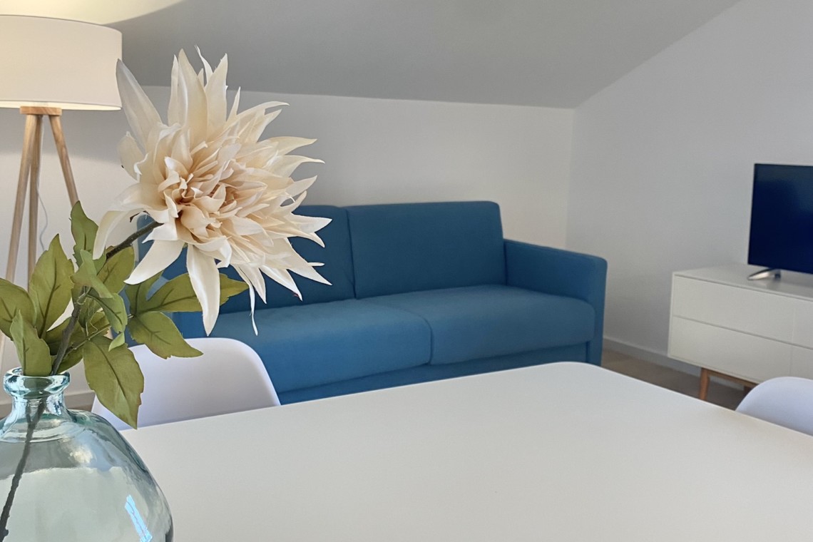 Moderne FeWo in Bad Wiessee mit blauem Sofa und stilvoller Deko, ideal für den Urlaub im Tegernsee Gebiet.