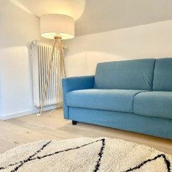 Helle FeWo in Bad Wiessee mit blauem Sofa, modernem Ambiente & gemütlicher Atmosphäre. Ideal für Erholungssuchende.