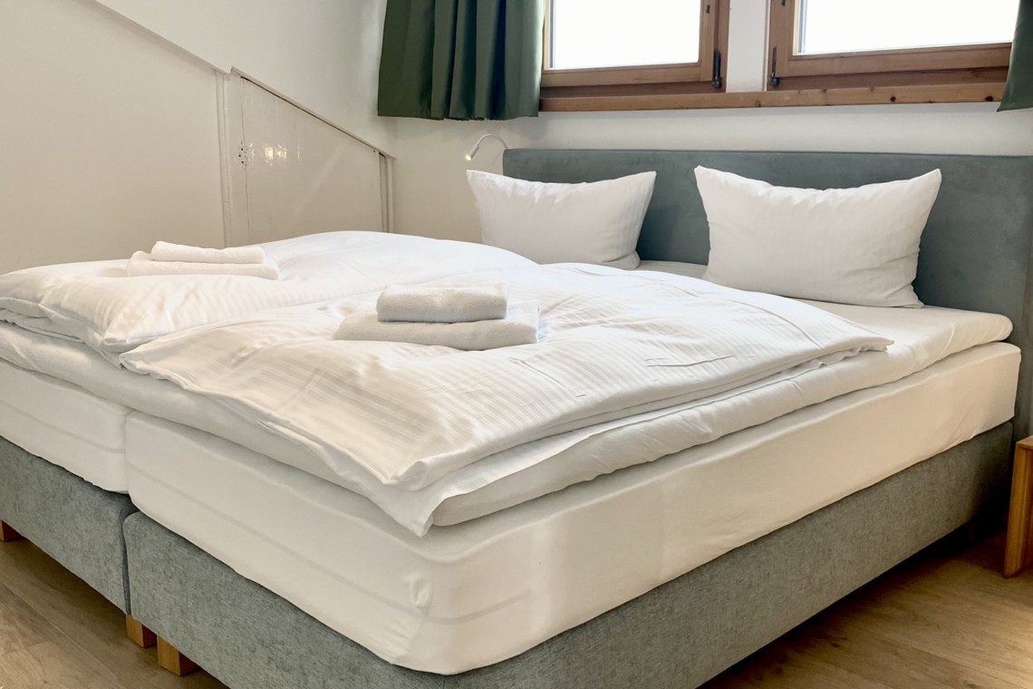 Helle FeWo in Bad Wiessee, gemütliches Doppelbett unter Dachfenstern. Ideal für Erholung und Urlaub.