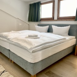 Helle FeWo in Bad Wiessee, gemütliches Doppelbett unter Dachfenstern. Ideal für Erholung und Urlaub.