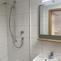 Modernes Bad in Ferienwohnung, Bad Wiessee. Helle Fliesen, Dusche, Waschbecken. Ideal für Ihren Komfort.