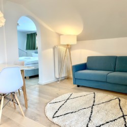 Helle, moderne FeWo in Bad Wiessee mit gemütlichem Sofa, stilvoller Einrichtung & sanfter Beleuchtung.