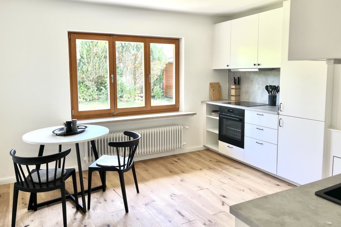 Moderne Küche in einer Ferienwohnung in Rottach-Egern mit hellem Interieur und Blick ins Grüne. Ideal für Erholung und Arbeit.