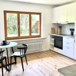 Moderne Küche in einer Ferienwohnung in Rottach-Egern mit hellem Interieur und Blick ins Grüne. Ideal für Erholung und Arbeit.