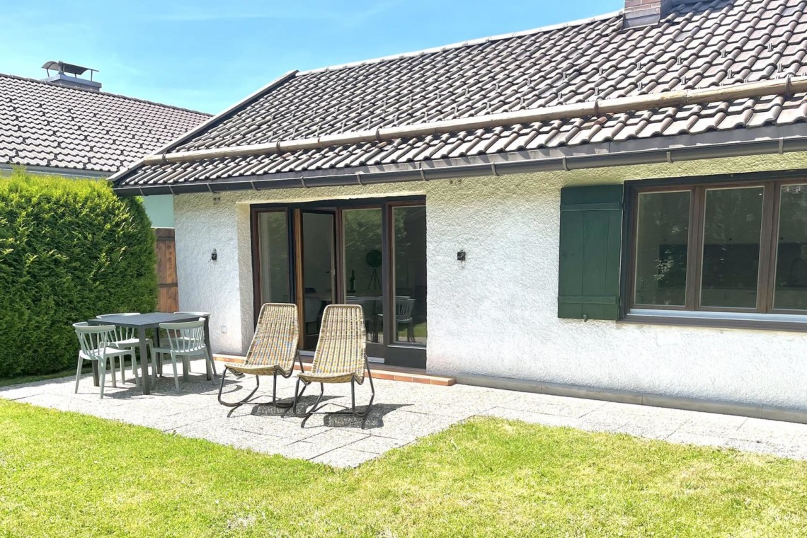 Gemütliche Terrasse einer Ferienwohnung in Rottach-Egern, umgeben von Grün und ideal für Erholung.