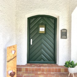Gemütliche Ferienwohnung in Rottach-Egern mit Willkommensschild und eleganter grüner Tür.